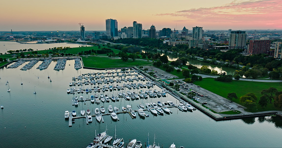 Aerial shot of Milwaukee, Wisconsin on a Fall evening, flying over sailboats in multiple marinas and looking over Veterans Park towards apartment buildings on the Lower East Side and Yankee Hill and the downtown office buildings of Juneau Town.