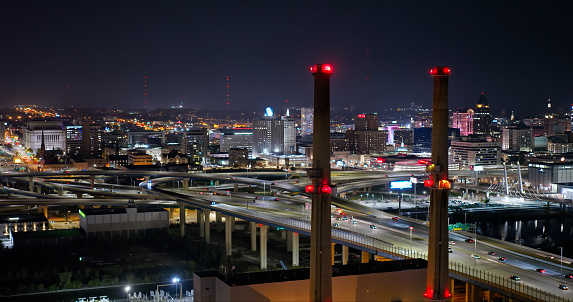 Aerial shot of Milwaukee, Wisconsin at night, looking past power plant smoke stacksacross the Marquette Interchange where I-44, I-94 and I-794 meet. \n\nAuthorization was obtained from the FAA for this operation in restricted airspace.