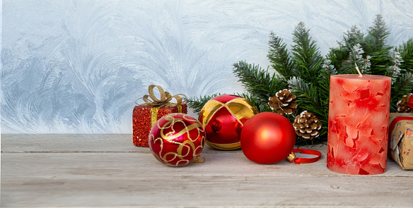 Christmas mood, New Year background. Christmas fir branches, red Christmas balls, a candle and gift boxes on a background of hoarfrost patterns with copy space. Holiday atmosphere.