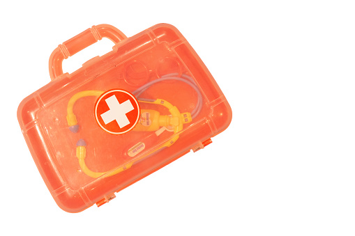 A faded orange plastic toy doctor's case and set shot isolated on a white background with copy space available
