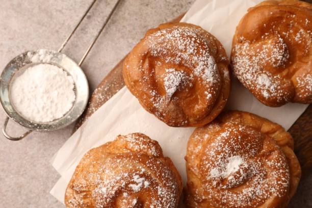 istock Delicious profiteroles with powdered sugar on grey table, flat lay 1809936172