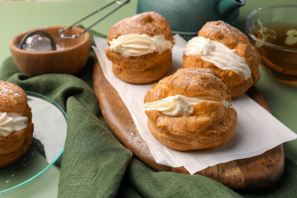 istock Delicious profiteroles filled with cream and tea on green background 1809937245