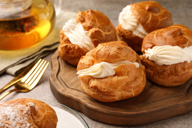 istock Delicious profiteroles filled with cream on grey table 1809937253