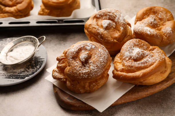 istock Many delicious profiteroles with powdered sugar on grey table 1809937278