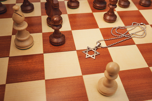 Jewish religious symbol star of David with chess pieces kings on a chessboard, close-up.