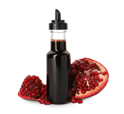 Bottle of pomegranate sauce and fresh ripe fruit on white background