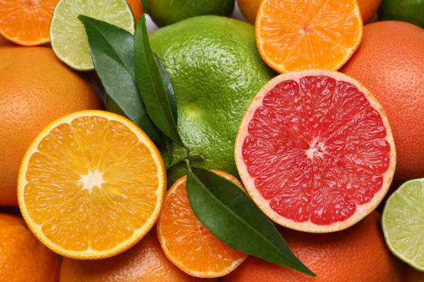 istock Different citrus fruits with fresh leaves as background, top view 1809961313