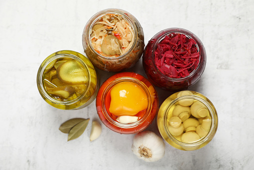 Many jars with different preserved products on white table, flat lay