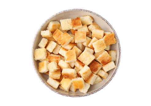 Delicious crispy croutons in bowl on white background, top view