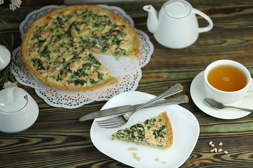 Delicious quiche pie with salmon fish and pine nuts. Cup of green tea
