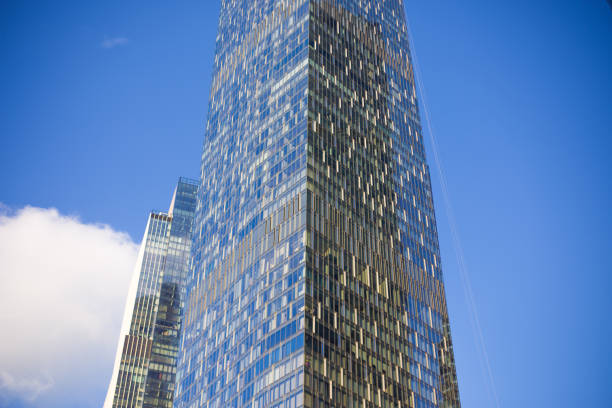 Corner of a glass multi-story office on a bright day with blue sky in the background