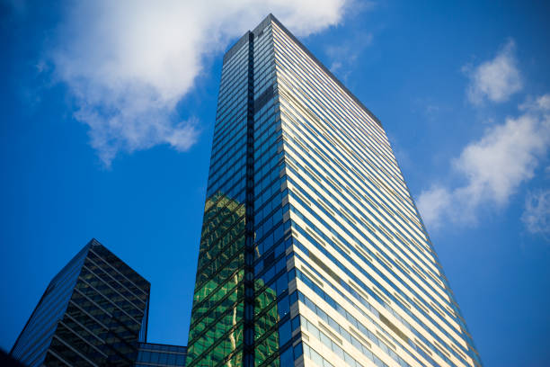 Glass high rise business building with offices. Facade of a multi storey modern house with blue sky and clouds in the background