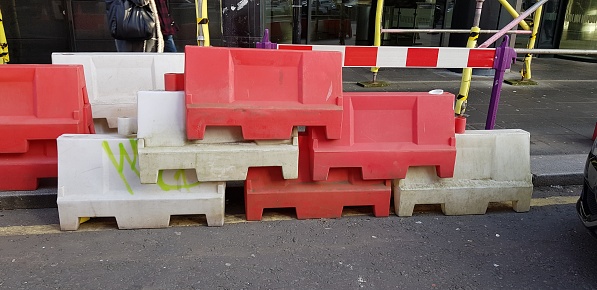 Plastic traffic construction safety barriers or separators piled up at a street, Glasgow Scotland England UK