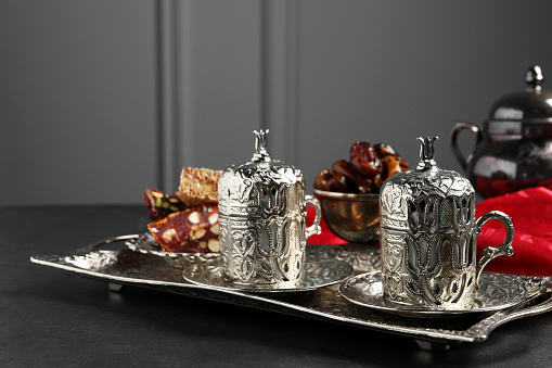 Tea, Turkish delight and date fruits served in vintage tea set on black table, space for text