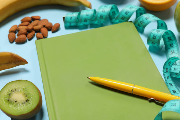 istock Weight loss concept. Composition with notebook, measuring tape and different products on light blue background, closeup 1810016535