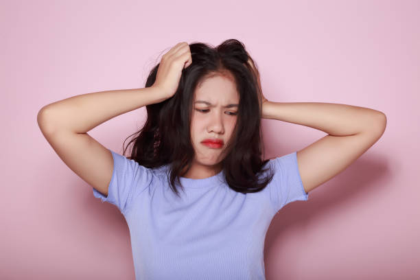 istock Asian woman making a stressed expression Standing alone on a light pink background. Beautiful young woman is feeling stressed. 1810022243
