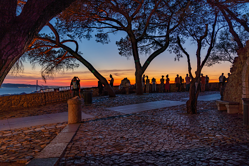 Tourists are enjoying the scenery of old castle - Castelo de S. Jorge at dusk, Portugal.