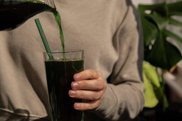 kobiece ręce trzymające organiczny napój detoksykacyjny spirulina z niebiesko-zielonych alg w szklanym proszku spożywczym. zdrowy koktajl białkowy koktajl z chlorelli. witaminy i minerały w diecie. bogaty w prebiotyki i antyoksydanty suplement diety  - chloroplasty zdjęcia i obrazy z banku zdjęć