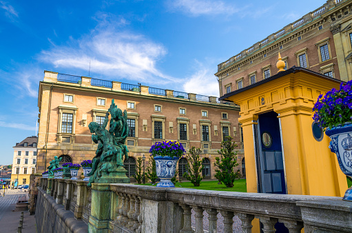 Stockholm, Sweden, May 29, 2018: Royal Palace eastern facade (Stockholms slott, Kungliga slottet) Norrbro side, fence, statue, garden