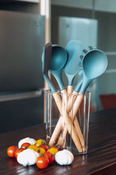 four blue spoons and three wooden utensils sitting on a table with tomatoes
