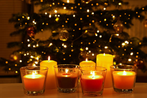 istock Beautiful burning candles on table in room with Christmas tree. Cozy winter 1810055460