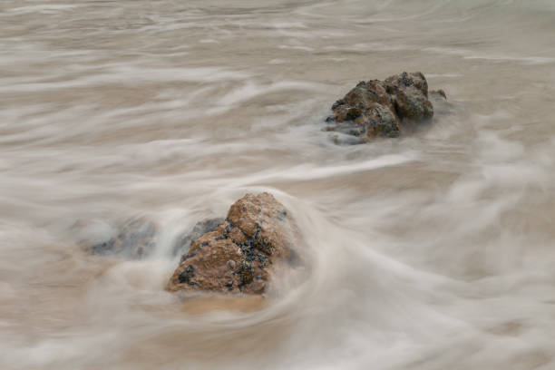 Waves sliding over the rocks of the Mediterranean sea making a white wake created by the long exposure of the shot.Selective focus, out of focus area