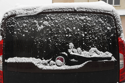 Car with rear windscreen wipers covered with snow outdoors on winter day