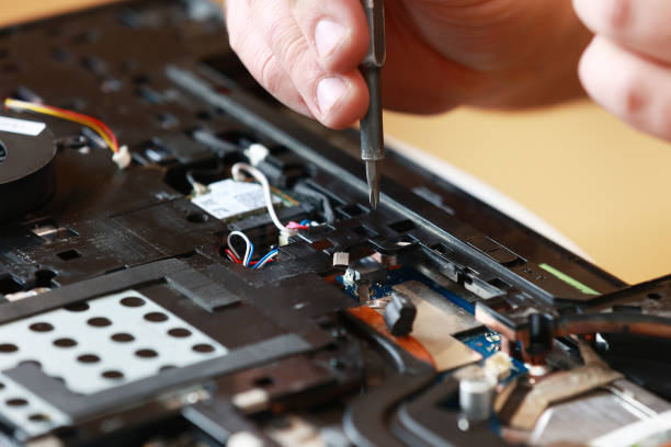 istock Repaiman with screwdriver fixing disassembled laptop parts. Technical support and fixing gadgets problems. Servicing, repairing, cleaning, maintaining computers. Repair shop. Hardware maintenanc 1810102293