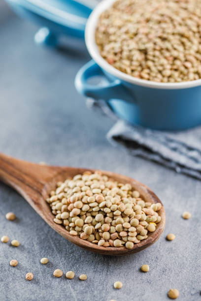 istock Uncooked lentil legumes in wooden spoon on kitchen table. 1810111347