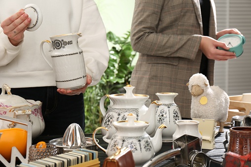 Women near table with different stuff indoors, closeup. Garage sale