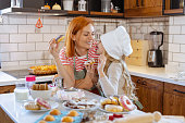 Mom and her little cute girl tasting home made sweets in the kitchen