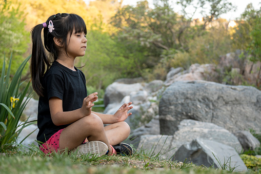 Little latin girl practicing yoga in a natural environment