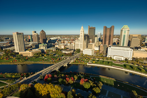 Aerial still image of Downtown Columbus, with Discovery Bridge and East Bank Park, taken by a drone on a clear, Fall day in Ohio.