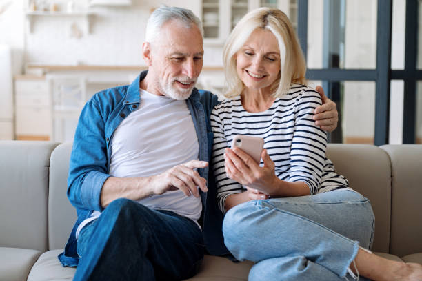istock Middle aged smiling man and woman using smartphone for online shopping 1810153646