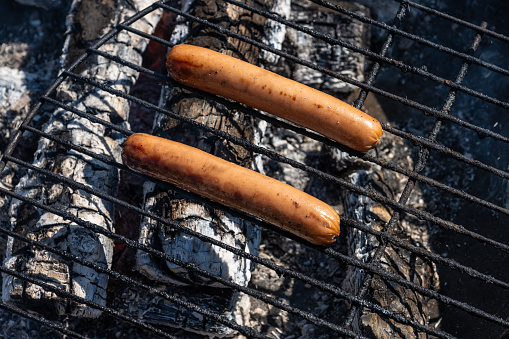 Two hot dogs on a barbecue.