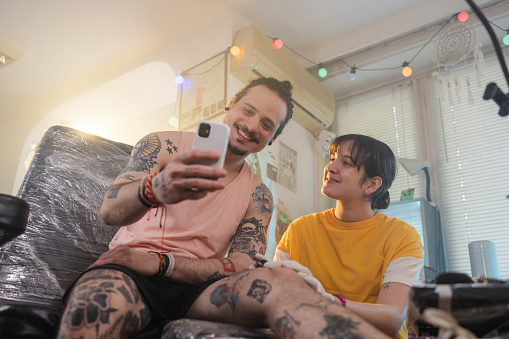 Photo of a smiling tattoo artist and her male client getting tattoo ideas on the internet