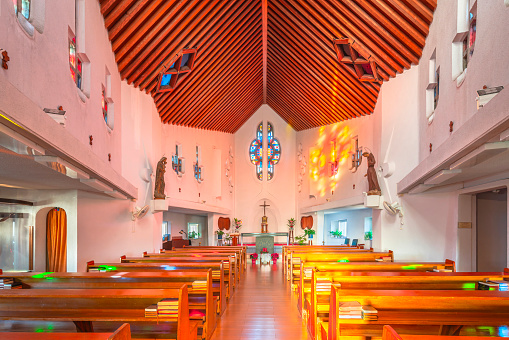nagasaki, kyushu - dec 12 2022: Interior of St Filippo Nishizaka Church created in 1962 by Japanese architect Kenji Imai with a wooden ceiling and colorful stained glass windows that let in sunlight.