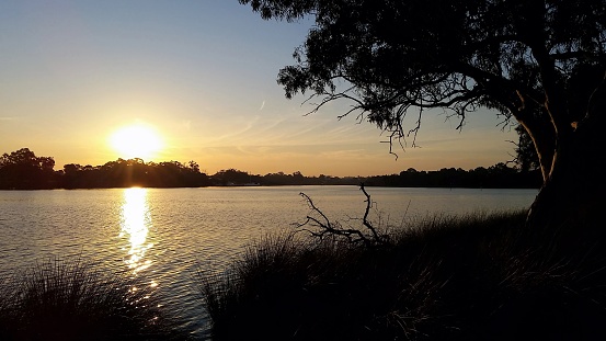 Peaceful scene with sun setting behind trees on the Swan River Perth