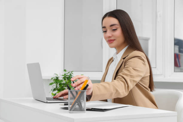 istock Young female intern working with laptop at table in office 1810222557