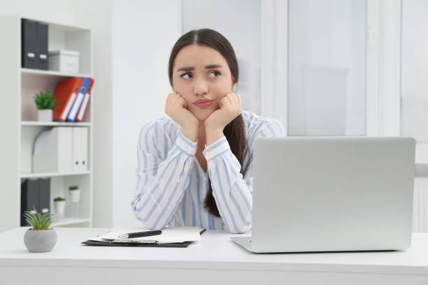 istock Unhappy young female intern at table in office 1810223083