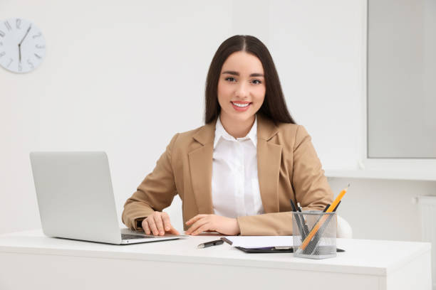 istock Young female intern working with laptop at table in office 1810223091