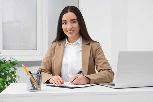 istock Young female intern working with laptop at table in office 1810224160