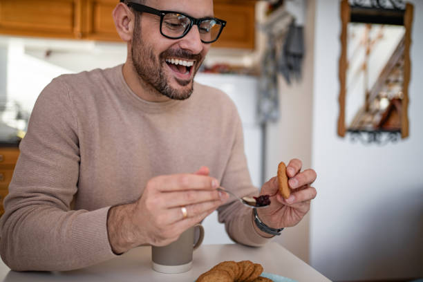 istock A middle-aged white man is drinking coffee and eating a biscuit and jam for breakfast 1810268478