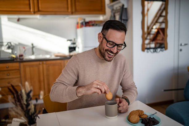 istock A middle-aged white man is drinking coffee and eating a biscuit and jam for breakfast 1810268483