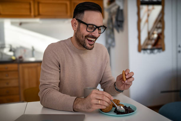 istock A middle-aged white man is drinking coffee and eating a biscuit and jam for breakfast 1810268497