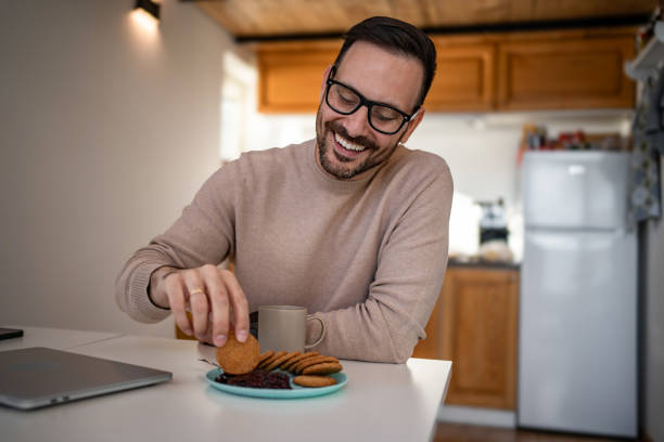 istock A middle-aged white man is drinking coffee and eating a biscuit and jam for breakfast 1810268880