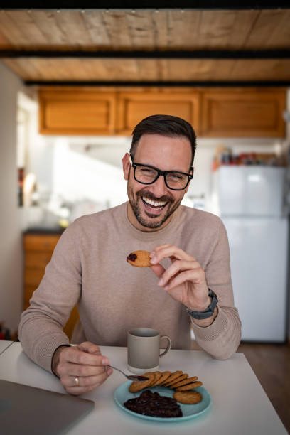 istock A middle-aged white man is drinking coffee and eating a biscuit and jam for breakfast 1810269011