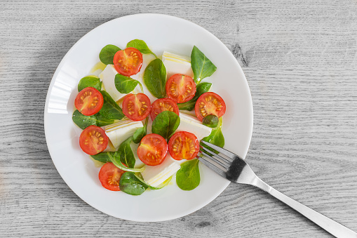 Cherry tomato salad with lamb's lettuce, fresh cheese seasoned with salt and extra virgin olive oil, healthy food concept.