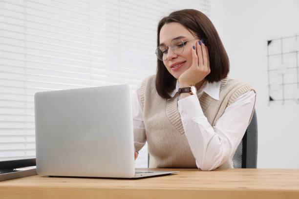 istock Happy young intern working with laptop at table in modern office 1810300126
