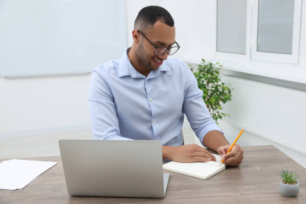 istock Happy young intern working at table in modern office 1810301163